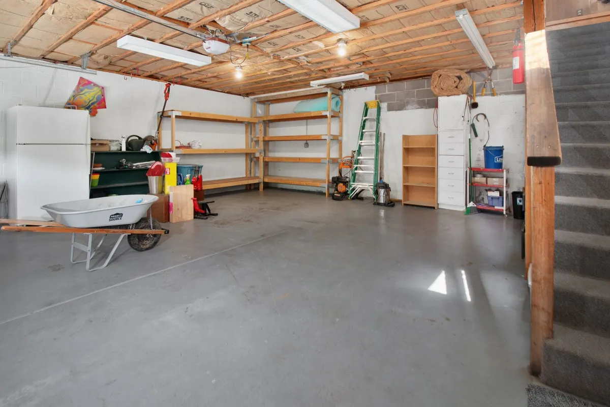 A spacious garage with organized shelves, tools, and a wheelbarrow, perfect for maintaining home projects.
